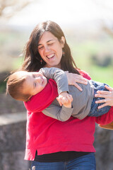 Mother carries her child in her arms as they play a game of spinning around on themselves.