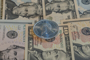 Silver coin, Krugerrand with US Dolars (USD)  notes in background.	