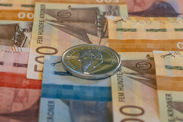 Silver coin, Krugerrand with Norvegian Krone notes in background.	
