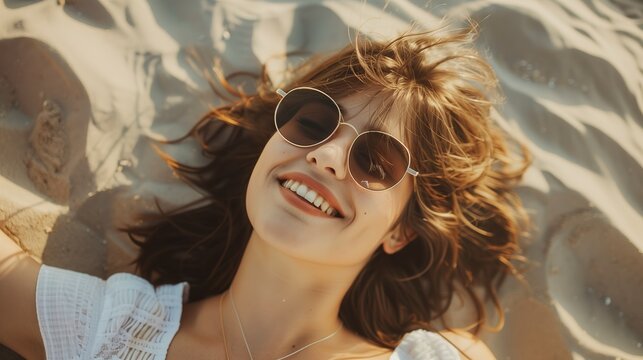 A relaxed portrait of a beautiful smiling brunette young natural woman wearing sunglasses