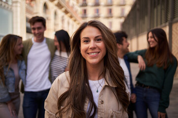 Portrait of Caucasian attractive woman looking smiling at camera in front unfocused group of people...
