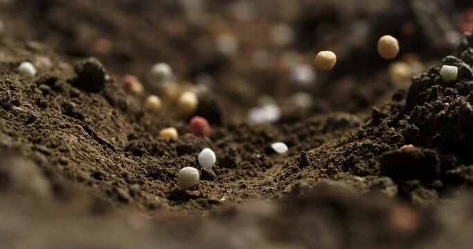 Super slow motion macro of natural bio fertilizers granules added for field ground soil by agricola machinery before plant in ecological rural farmland agricultural plantation at 1000 fps