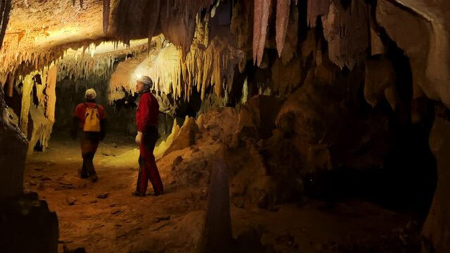 A group of speleologist inside a cave, illuminated by headlamps, exploring the depths of a mysterious underground system. High quality 4k footage