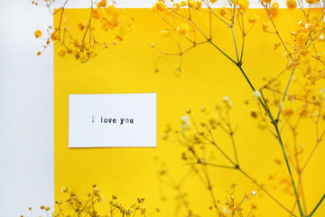Small yellow flowers on branches next to a card for inscriptions on a yellow background