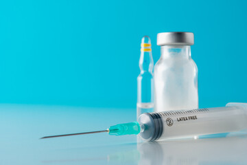 Vaccine vial glass with a syringe on blue background. Medicine vaccination concept. World pandemic...