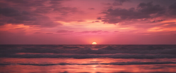 A pink sunset over the ocean, with waves gently lapping at shore and a distant sun setting behind...