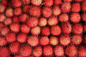 A close up of many red ramboutans in a Thai market. - 777487841