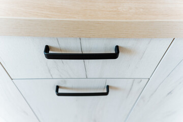 Close up of rectangular wooden cabinet with black handles