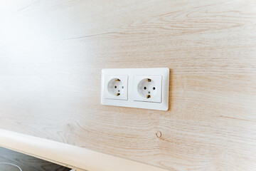 Two white wall sockets installed on a hardwood wall
