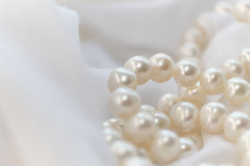 The soft focus on the pearls exudes a gentle, soothing aura on a pristine white fabric. It subtly champions the cause of natural beauty in a world obsessed with manufactured perfection.