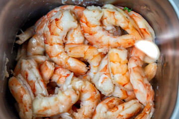 Bowl filled with shrimp and sauce placed on a wooden table