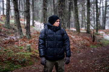 Portrait of Hispanic Peruvian adventurer in snowy woodland, surrounded by tall pines.