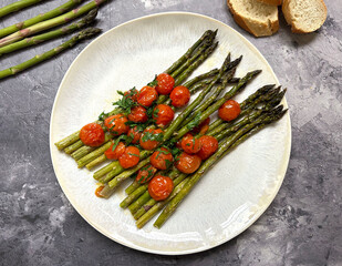 Green asparagus with Parmesan, cherry tomatoes, olive oil, garlic, parsley, salt, and pepper. A healthy, delicious and quick to prepare meal.