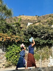 Local women carrying water containers on their head in Guatemala