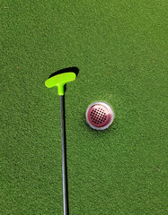 Mini golf putter and hole on green artificial turf grass