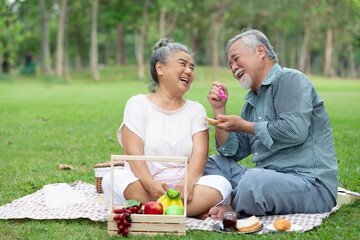 senior couple have a picnic in the park and eating bread with grape jam