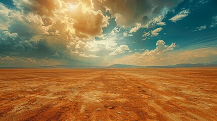 A vast, empty desert with a few clouds in the sky. The sky is a mix of blue and orange, creating a warm and peaceful atmosphere - obrazy, fototapety, plakaty