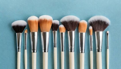 Makeup brushes set in row. Professional makeup tools on pastel blue background. Set of glamour make up brushes.