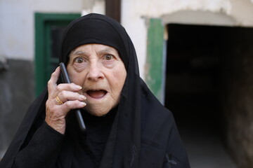 Surprised looking senior Islamic woman getting a phone call 