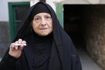 Senior muslim woman smoking a cigarette 