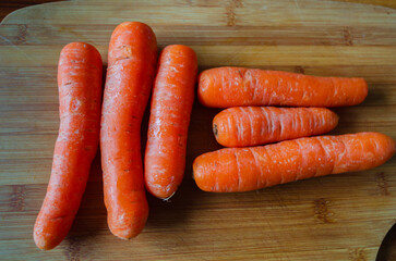 Unpeeled carrots on a wooden chopping board