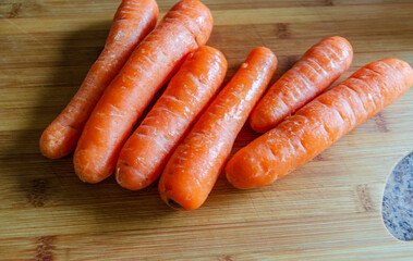 Unpeeled carrots on a wooden chopping board