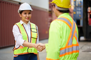 workers or engineers shaking hands before starting to work in containers warehouse storage