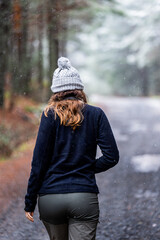 Back view of adventure enthusiast in gray hat, black fleece, exploring snowy forest.