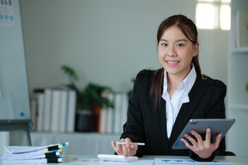 Portrait of beautiful asian young Business woman working audit and calculating expense annual financial report balance sheet statement,doing finance making notes on paper graph data checking document.