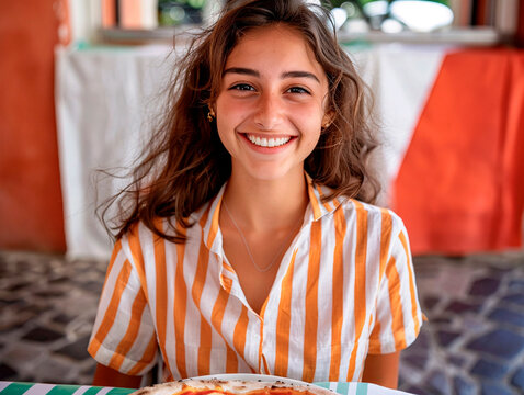 Cheerful young brunette holding a pizza on a terrace with a refreshing vibe