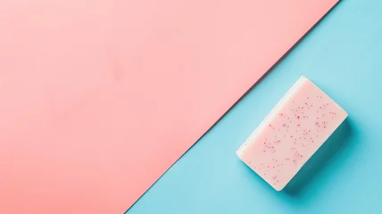 Rolgordijnen Pink bar of soap with exfoliating grains rests on two-tone blue and background © Artyom