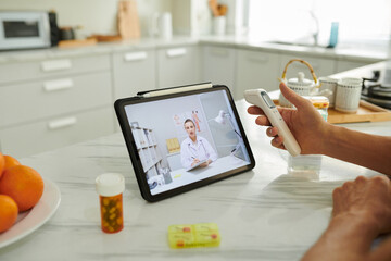 Man measuring temperature when talking to doctor using telemedicine service