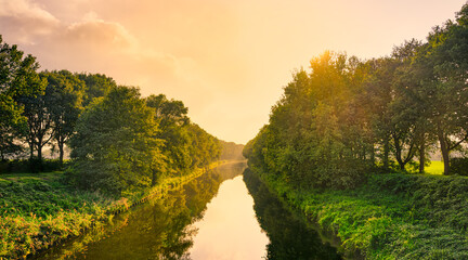 Sunset lighting slightly foggy canal "Wilhelminakanaal" near the village of Aarle-Rixtel, The Netherlands.