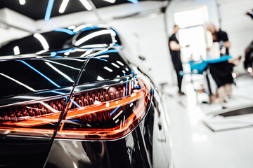 Details from vehicle polishing and detailing service in a modern car workshop. Brightly lit workspace with large led lights. High quality car valeting concept.