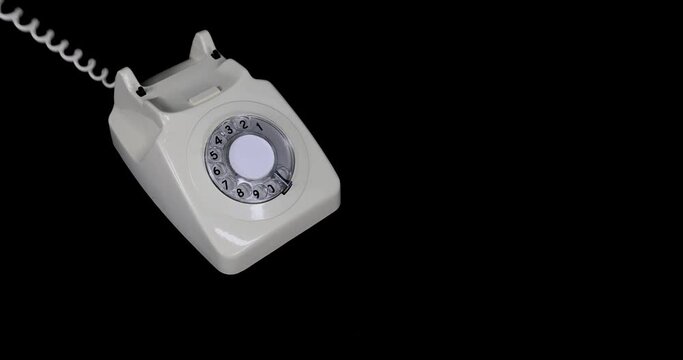 An old style phone being picked and and answered while ringing by a mans hand, then putting the phone back down again, on a dark black background