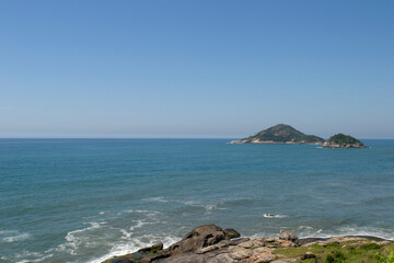 Mountains, vegetation and the ocean with clear blue waters of Praia de Grumari, located in the city of Rio de Janeiro.