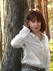 A girl with a square hairstyle in a white shirt near a tree in the park
