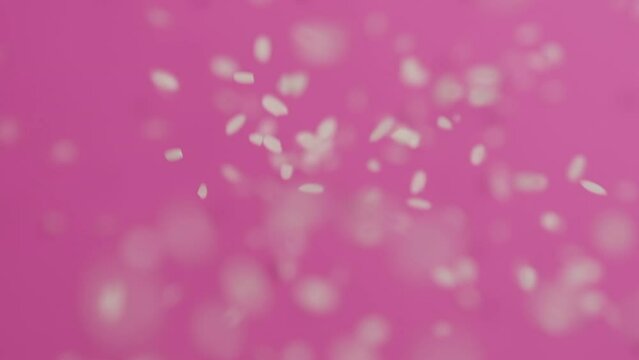 Rice falling on a pink background