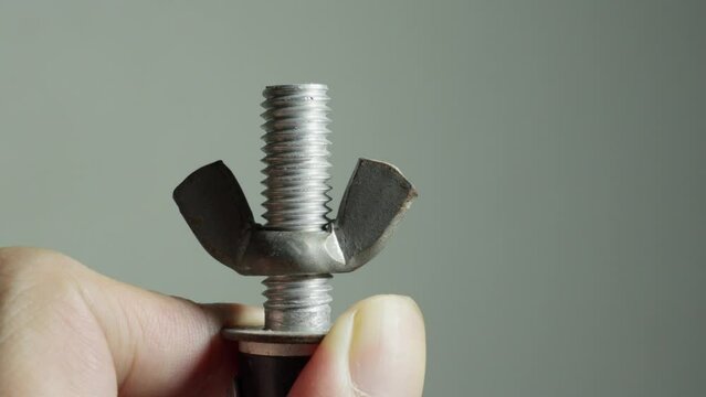 Wing nut turning to come off screw, close up
