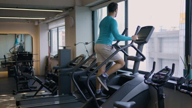 Sportsman Burn Calories Exercising on Stepmill Stepper Exercise Machine at Empty Gym - wide shot