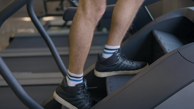 Man's Legs Close-up Doing Cardio on Stepmill Stepper Exercise Machine at Gym in Slow Motion
