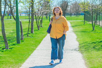 Plus size middle age lady in yellow shirt and blue jeans. Fashionable woman in casual style