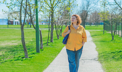 Plus size middle age lady in yellow shirt and blue jeans. Fashionable woman in casual style