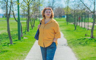 Plus size middle age lady in yellow shirt and blue jeans. Fashionable woman in casual style