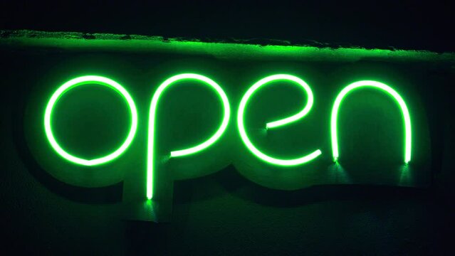 Green neon night plate changing brightness with the inscription Open
