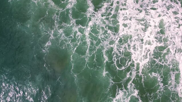 waves crashing by the seashore on stormy day aerial drone view of wild beach in the coastline of Spain.