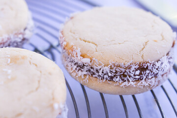 Close up of gluten free cornstarch cookies filled with dulce de Leche and grated coconuts on metal cooling rack