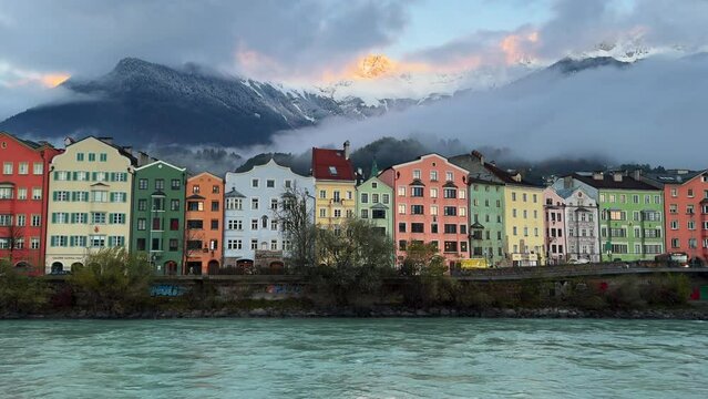 Innsbruck Austria colorful pastel buildings capital Tyrol Tyrolean Alps mountain backdrop the bridge over the Inn River cars bikes people sunny blue sky clouds October November autumn fall static wide