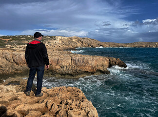 Wanderer (männlich) blickt auf das Meer im Nationalpark Kap Greco, Zypern - obrazy, fototapety, plakaty