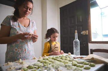 Authentic young pretty woman, mother and her little kid, daughter in the rural kitchen, sculpting...